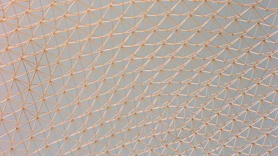 A lattice of repeated triangular struts against a pale sky